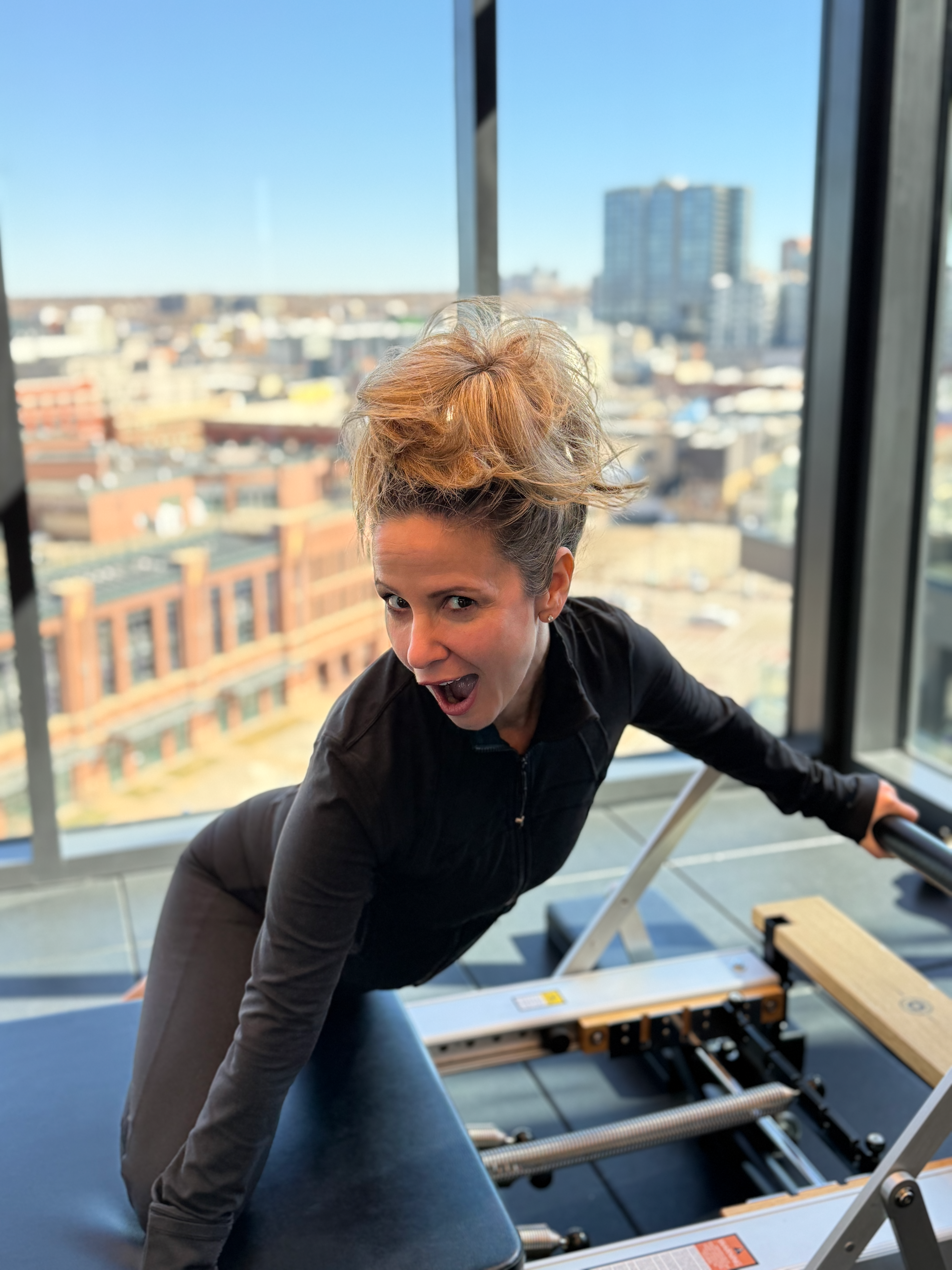 Rebecca striking an energetic pose on Pilates equipment